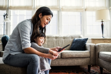 Eine Mutter, die mit ihrer kleinen Tochter ihr Telefon betrachtet