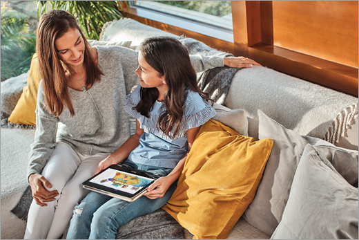 A mother and her daughter sit on a couch as the daughter uses Paint 3D on a laptop