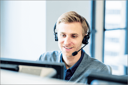 Photo of a man looking at a computer and wearing a headset.