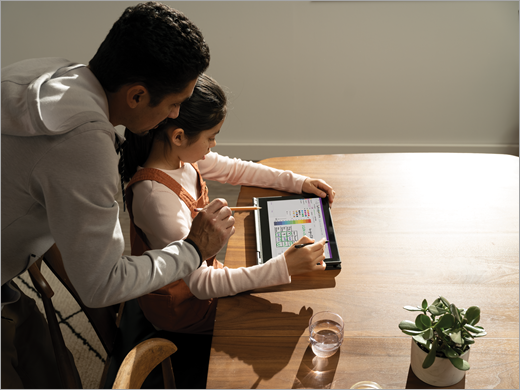 A father helps his daughter work on a tablet in Class Notebook