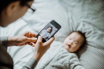 Egy anyuka fényképet készít a babájáról egy mobiltelefonnal