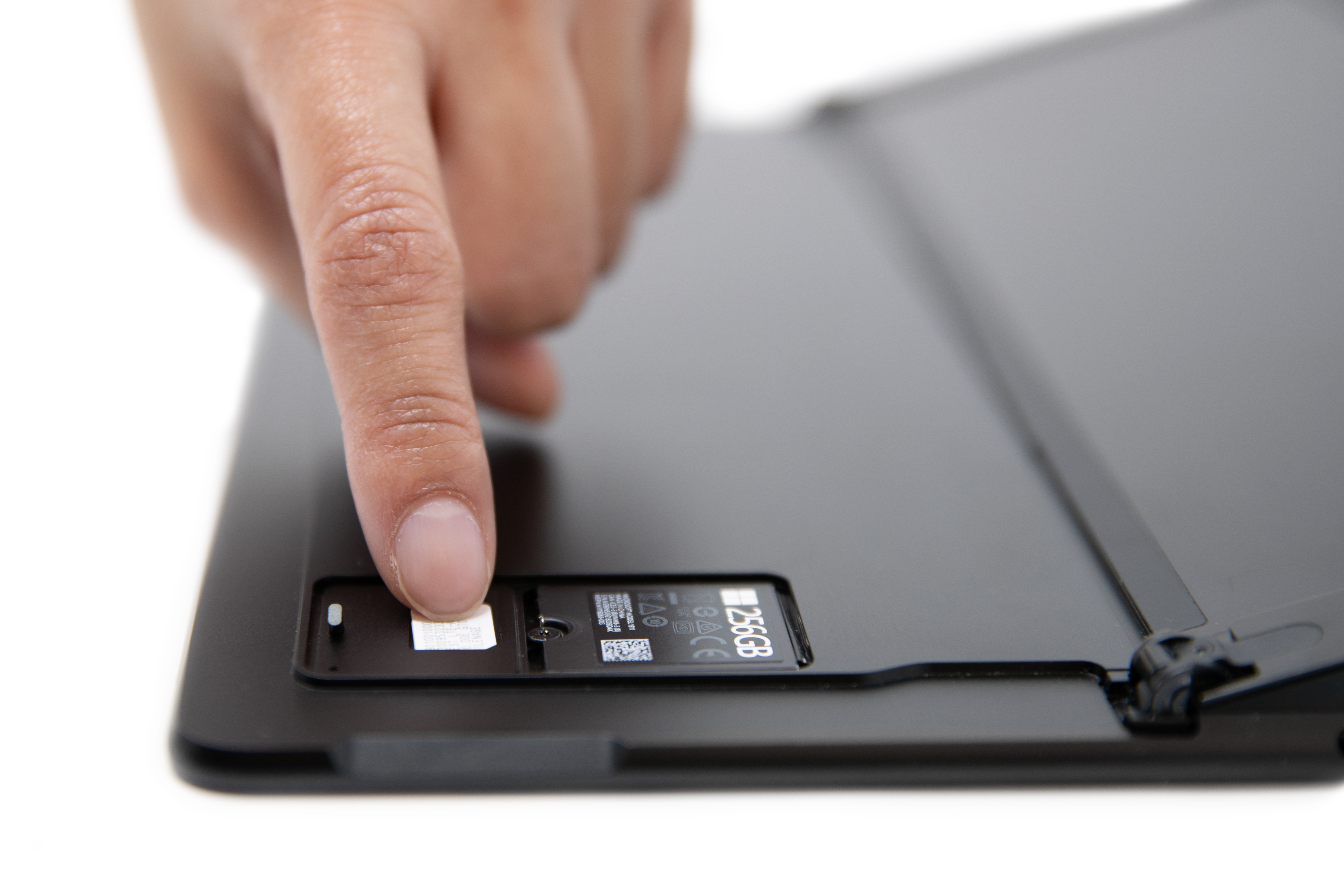 Seseorang meluncur dalam kartu SIM ke slot SURFACE PRO X SIM.