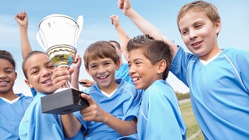 foto van een sportteam met kinderen die een overwinning vieren met een bokaal