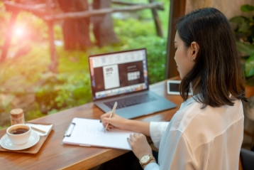 Een vrouw die een brief schrijft vlakbij haar laptop