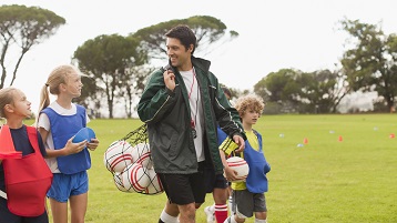 foto van een coach van een sportteam die sportspullen naar het veld brengt