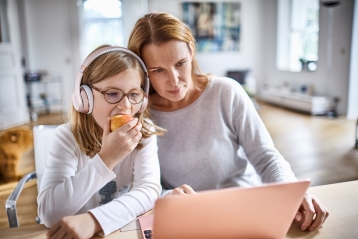 Een moeder en dochter die kijken naar een pc