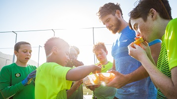 foto van een sportteam met kinderen die snacks eten