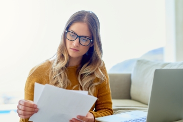 Een vrouw met bril die documenten bekijkt