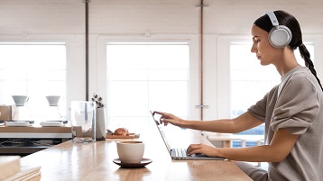 mulher usando fones de ouvido Surface trabalhando dentro do Surface Laptop2