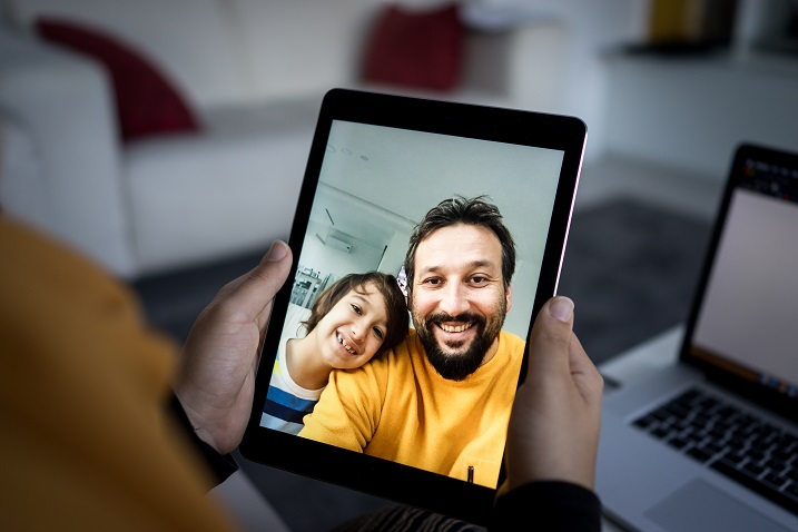 fotografija osebe, ki drži tablični računalnik z videoklicem